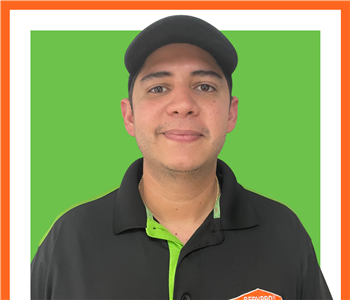 SERVPRO employee in uniform in front of green background